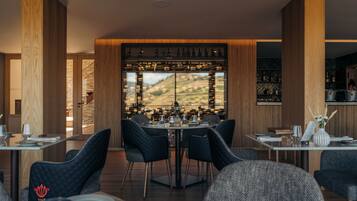 A restaurant with a view of vineyards, wooden paneling, and a wine rack with bottles.
