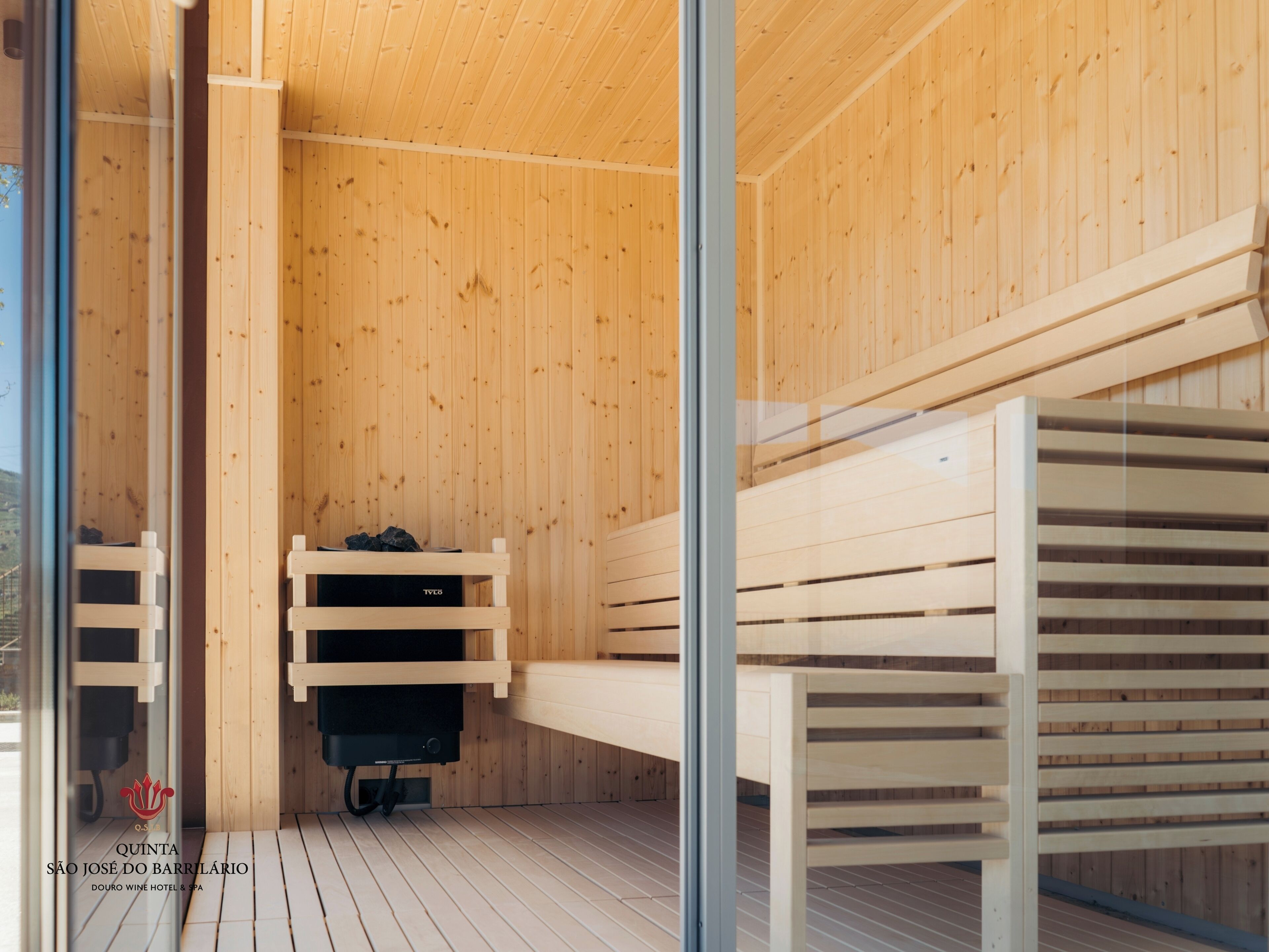 A sauna with wooden benches and a black heater.