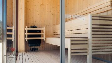A sauna with wooden benches and a black heater.