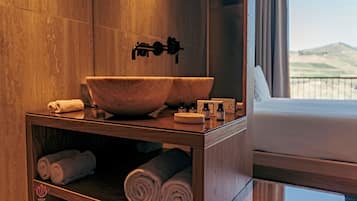 Un baño con tocador de madera, un lavabo grande y toallas.