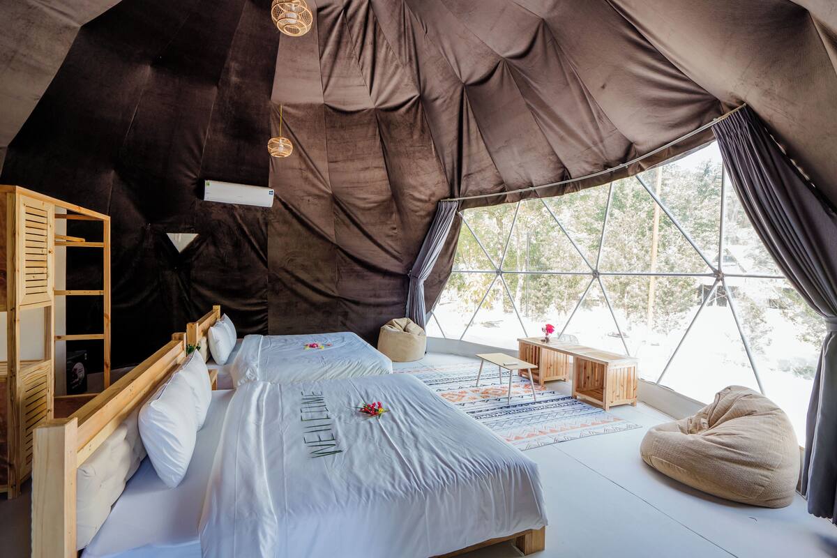 Una camera a tenda accogliente e luminosa, con un grande letto, mobili in legno e vista attraverso un'ampia finestra.