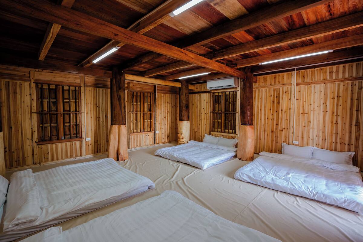 Una baita in legno con quattro letti, pareti di legno e un tetto spiovente con travi a vista.