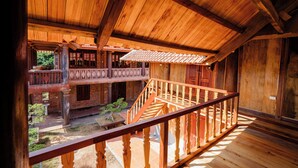 A wooden interior with a balcony, wooden railings, and a staircase.