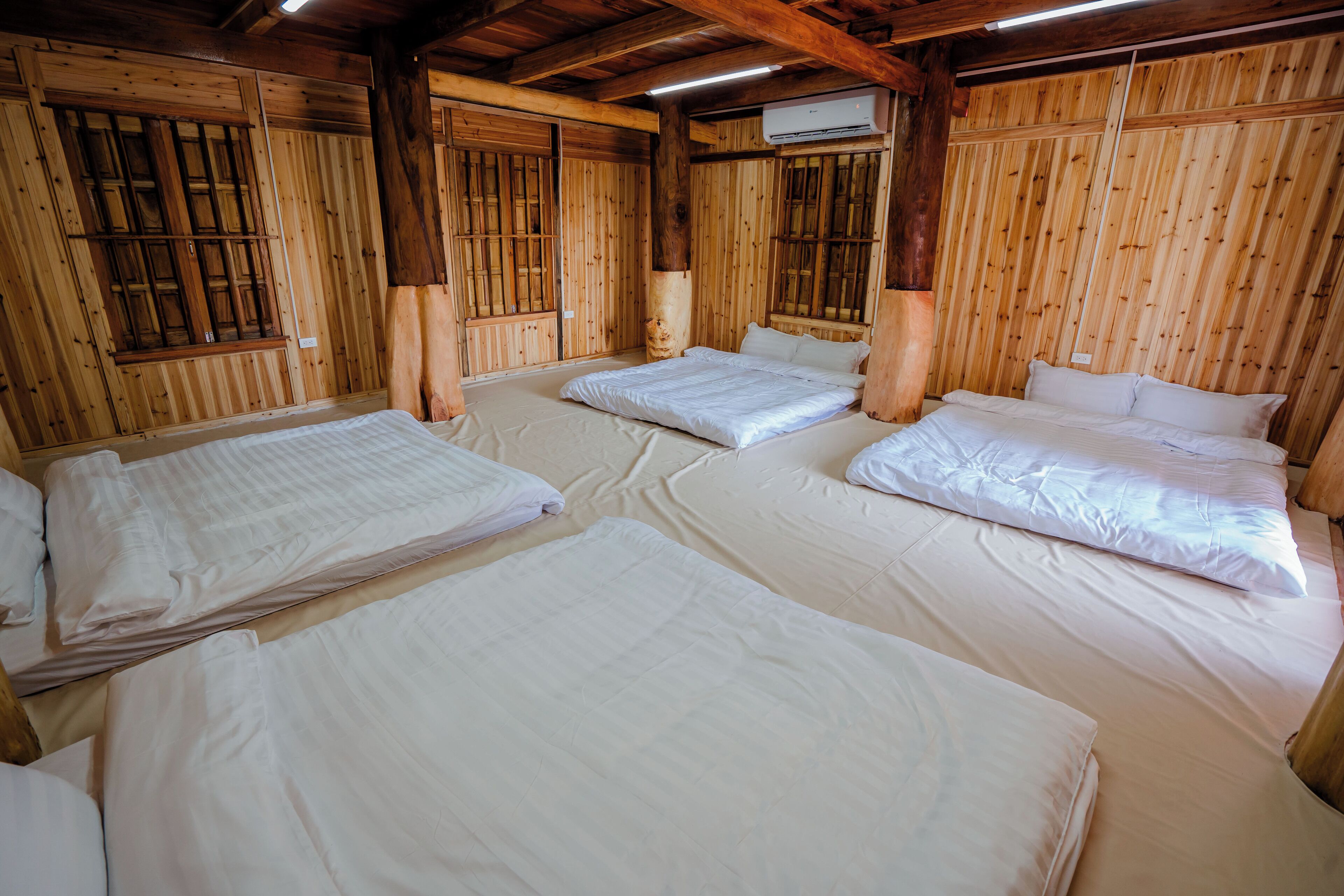 Una habitación con tres camas, paredes de madera y un ventilador de techo.