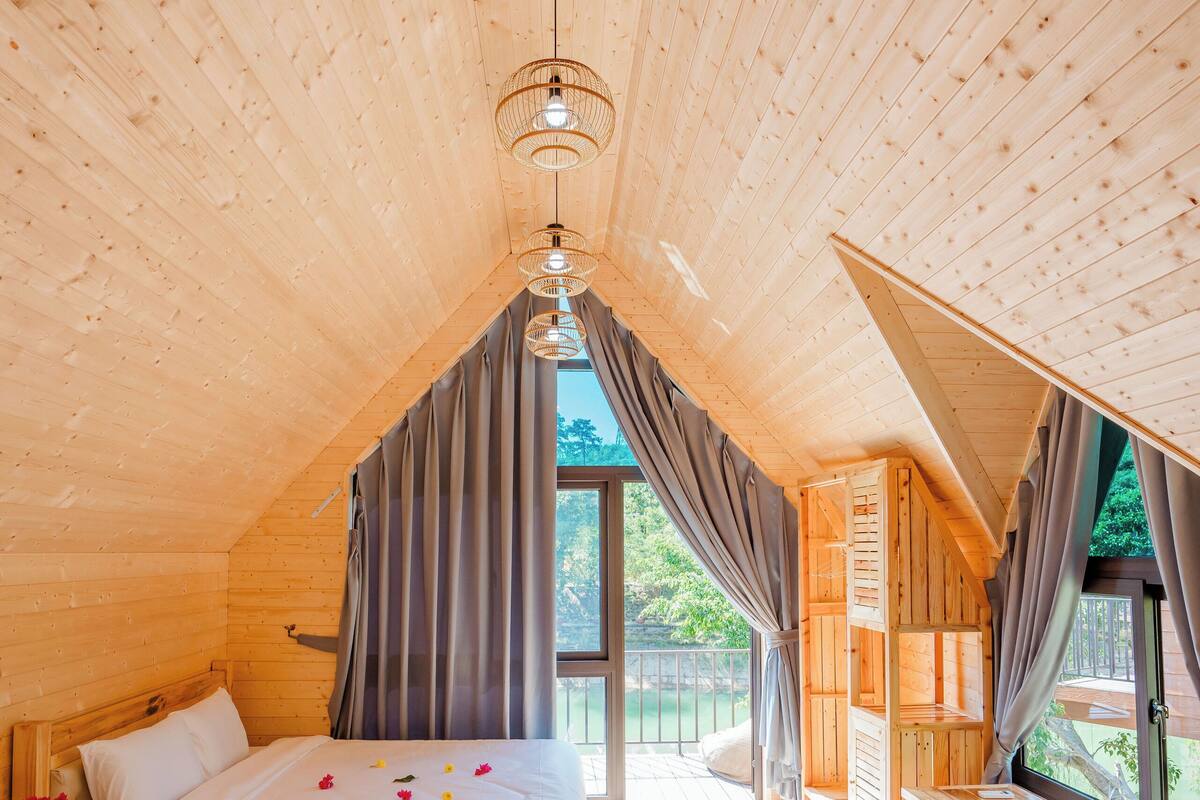 Una baita di legno con due letti, un'area pranzo e vista sulla natura.