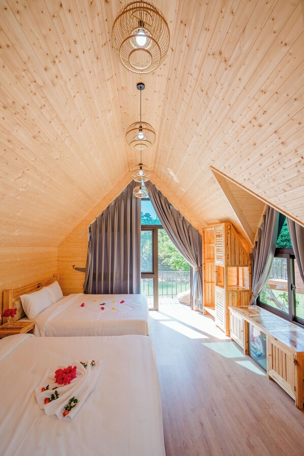 A wooden cabin with two beds, a dining area, and a view of the outdoors. - Bai Tu Long Mountain Resort (Van Don)