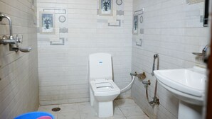 Un baño pequeño con inodoro, lavamanos y ducha. Paredes y suelo de azulejos.