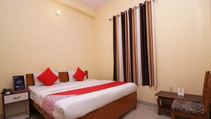 Una habitación de hotel con una cama, una mesita de noche, una silla y una pequeña mesa.