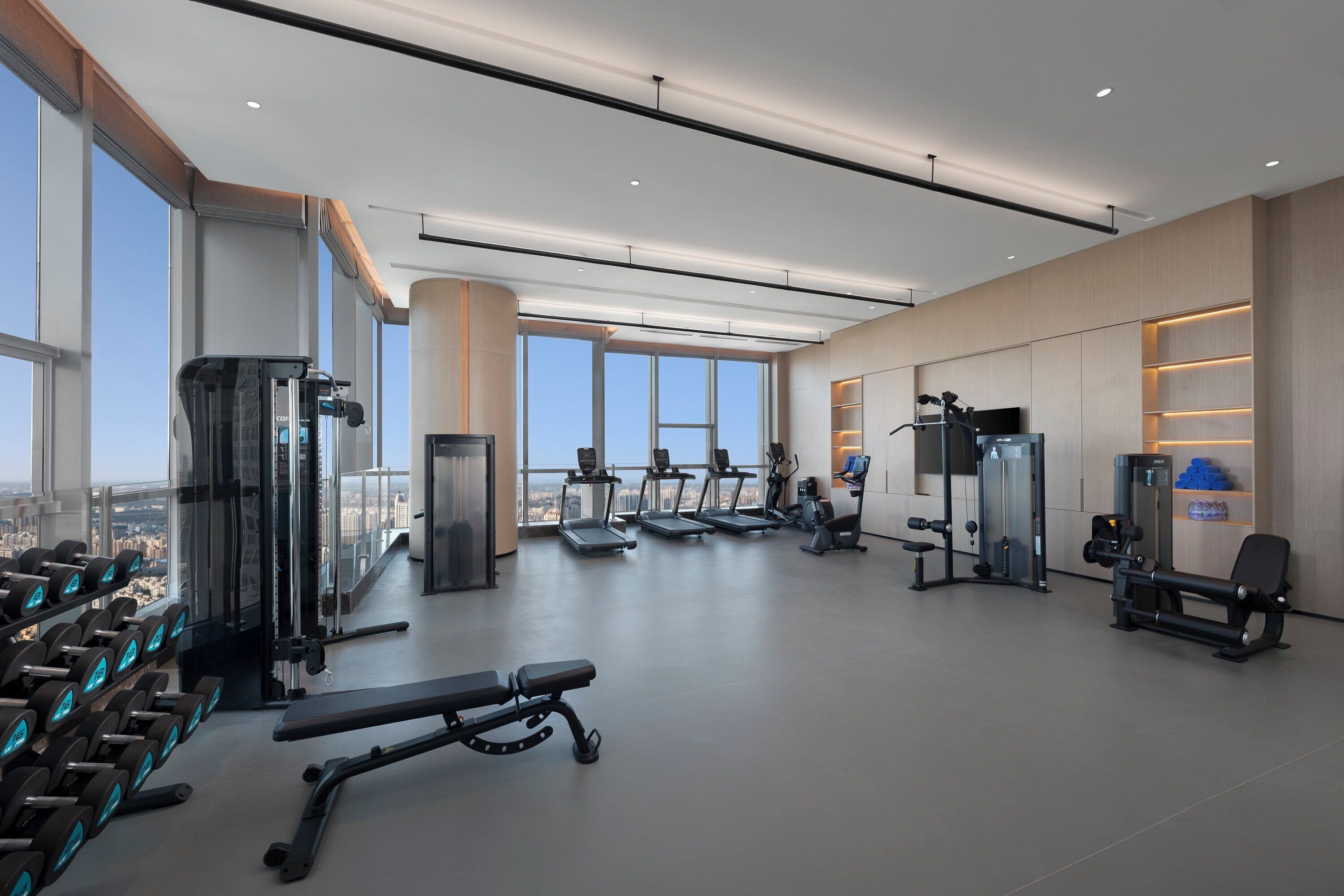 Un gimnasio moderno con cintas de correr, máquinas de pesas y mancuernas.