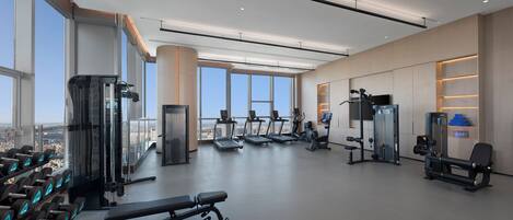 Un gimnasio moderno con cintas de correr, máquinas de pesas y mancuernas.