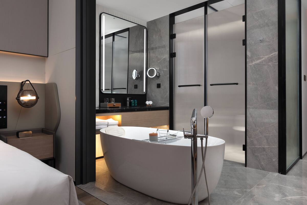 A modern bathroom with a freestanding bathtub, a large mirror, and a vanity with a sink and countertop.
