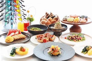 Variedad de alimentos para el desayuno, como waffles, pasteles y fruta, sobre una mesa.