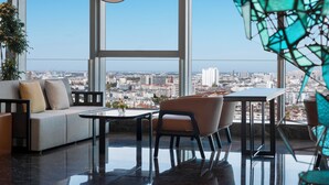 A modern living room with a sofa, chairs, a coffee table, and a view of a cityscape through large windows. - Crowne Plaza Taizhou City Center by IHG (Taizhou)