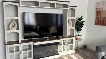 A modern living room with a flat-screen TV, built-in shelving, and a potted plant.
