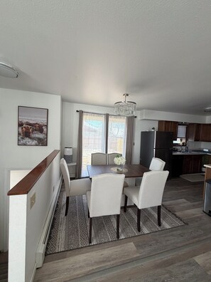 Una cocina moderna con armarios oscuros, una isla central y un comedor con mesa y sillas.