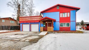 Et toetagers hus med rødt og blåt ydre, en veranda og to garageporte.