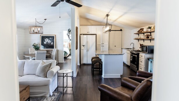 A modern kitchen with white cabinets, a black refrigerator, and a wooden countertop. - The Cottage at Cardinal Hill (Dahlonega)