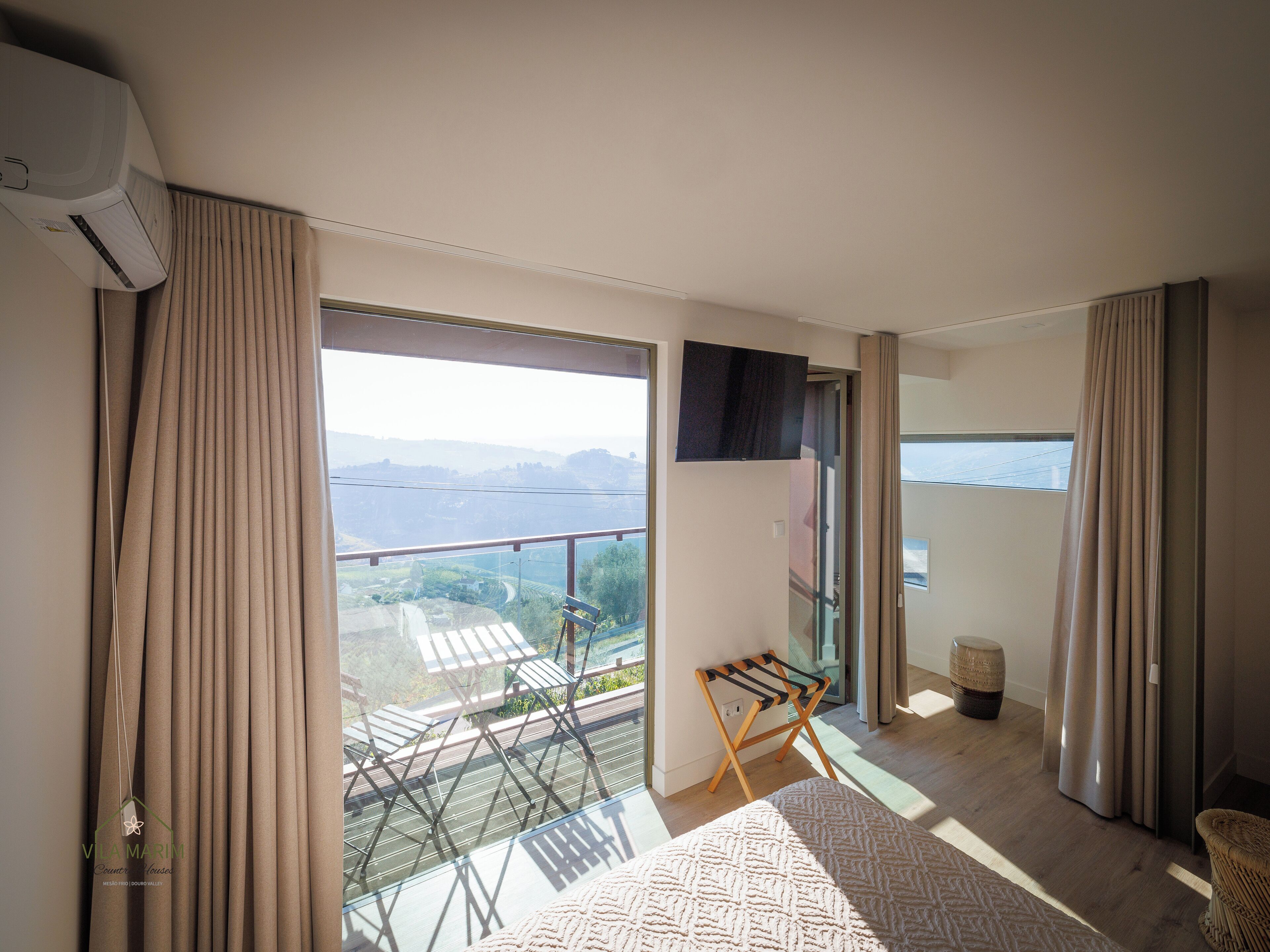A modern room with a large window, a flat-screen TV, and a wooden chair.