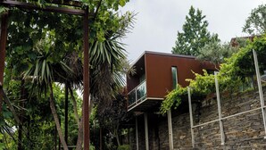 A modern building with a stone facade and a balcony overlooking a garden with grapevines. - Vila Marim Country House (Mesão Frio)