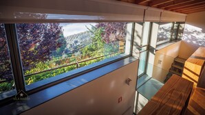 A modern interior with a large window overlooking a hillside garden. - Vila Marim Country House (Mesão Frio)
