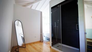 Un baño moderno con cabina de ducha de vidrio, suelo de madera y un espejo grande.