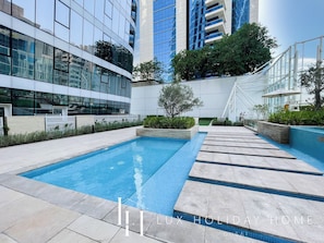 A modern building with a swimming pool, surrounded by greenery and a staircase. - LUX  Pad Executive Suite Canal View 5 (Dubai)