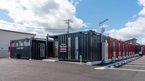 Ein Hotel mit modernem Design, das eine Reihe von Zimmern mit roten Akzenten und einen Parkplatz davor zeigt.