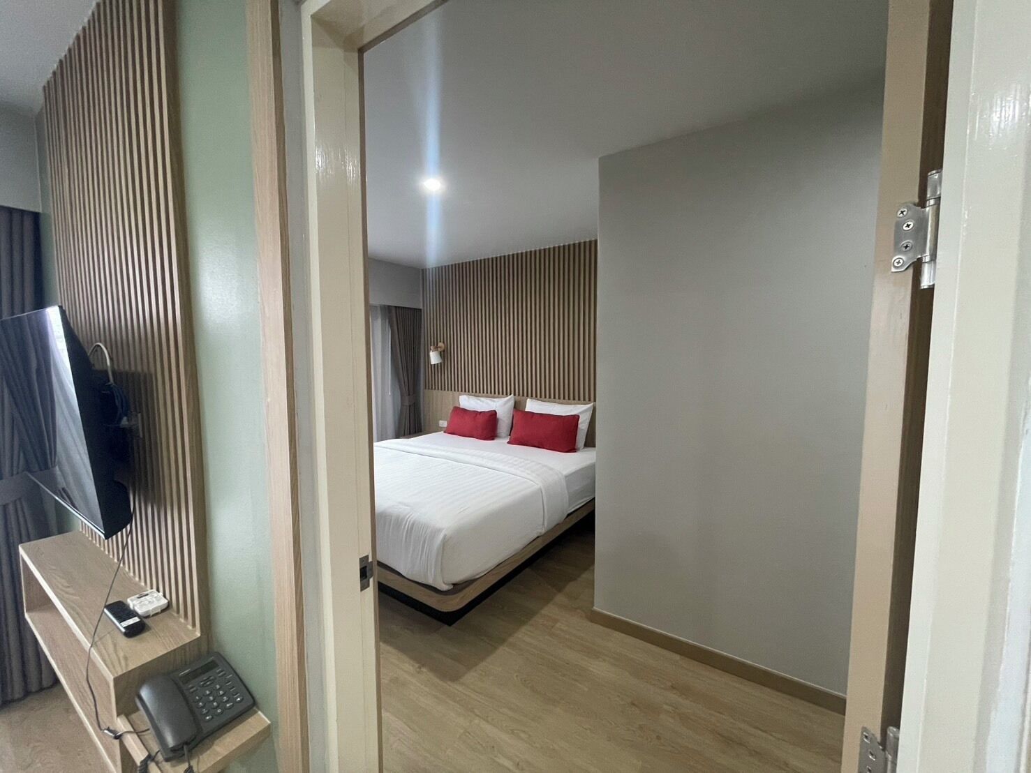 A hotel room with a bed, a desk with a phone, and a TV.