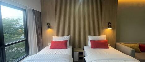A hotel room with two beds, a large window, and a city view.