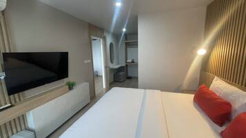 A modern hotel room with a large bed, a flat-screen TV, a small trash bin, and a mirror above the bed.
