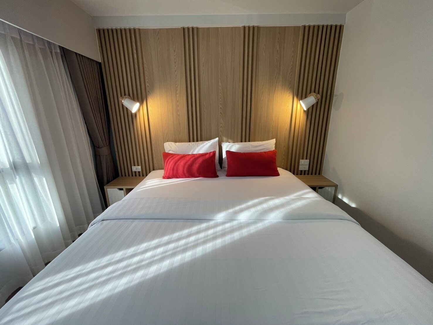 Camera d'albergo con un letto grande, due comodini e una testiera in legno.