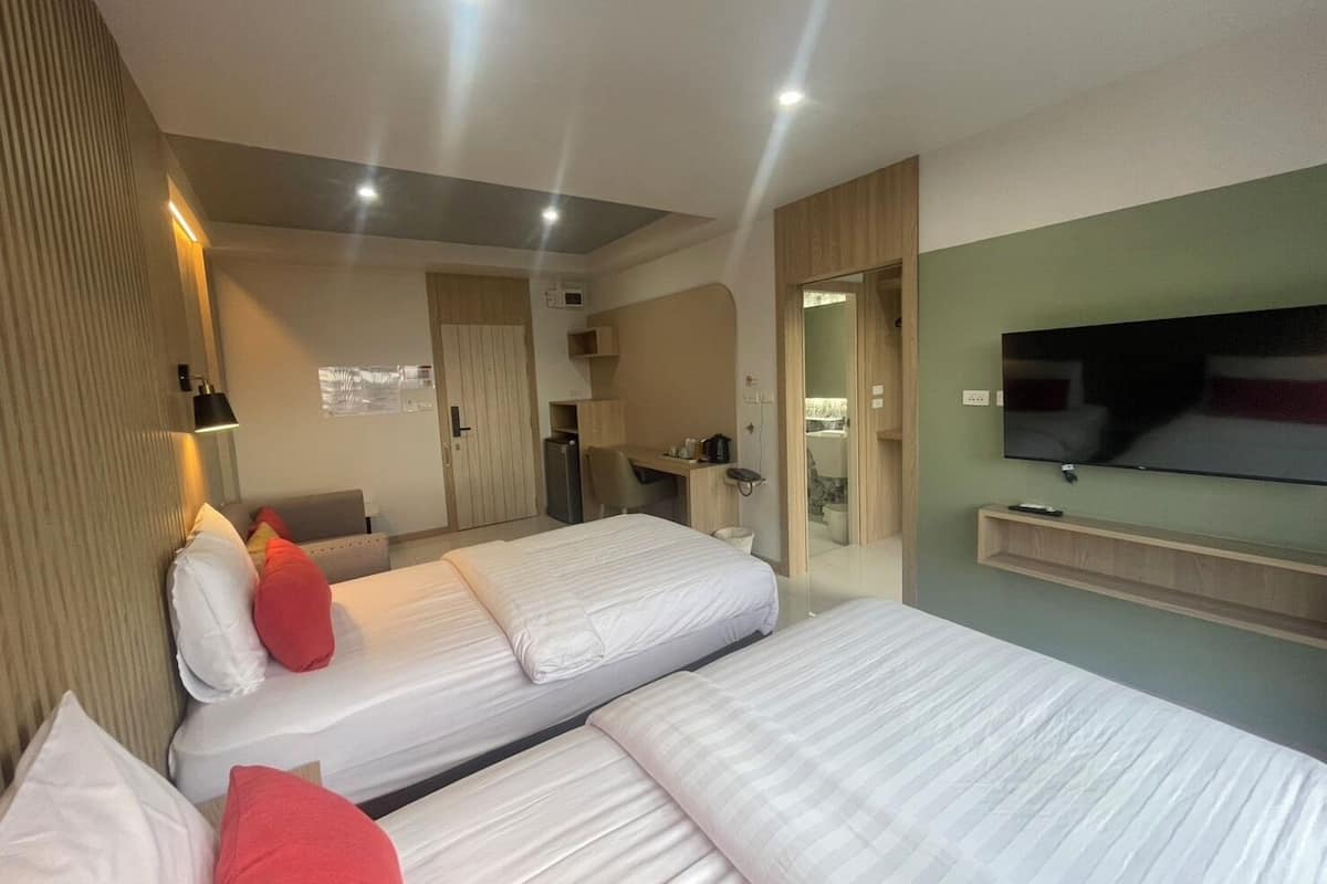 Una habitación de hotel con dos camas, televisión, escritorio y espejo.
