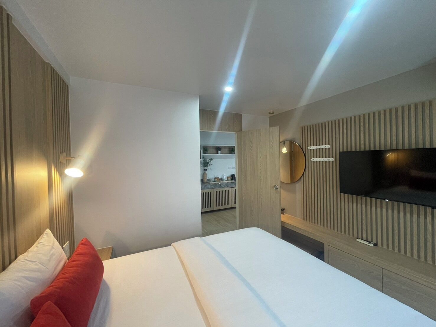 A modern hotel room with a large bed, a TV mounted on the wall, and a bathroom visible in the background.