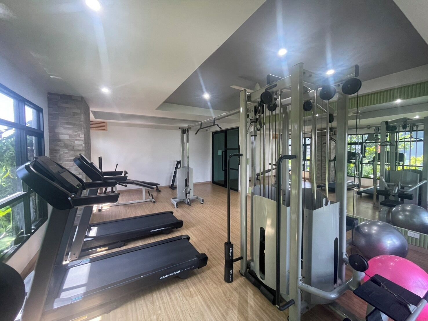 Uma academia com esteiras, uma máquina de pesos e bolas de exercício.