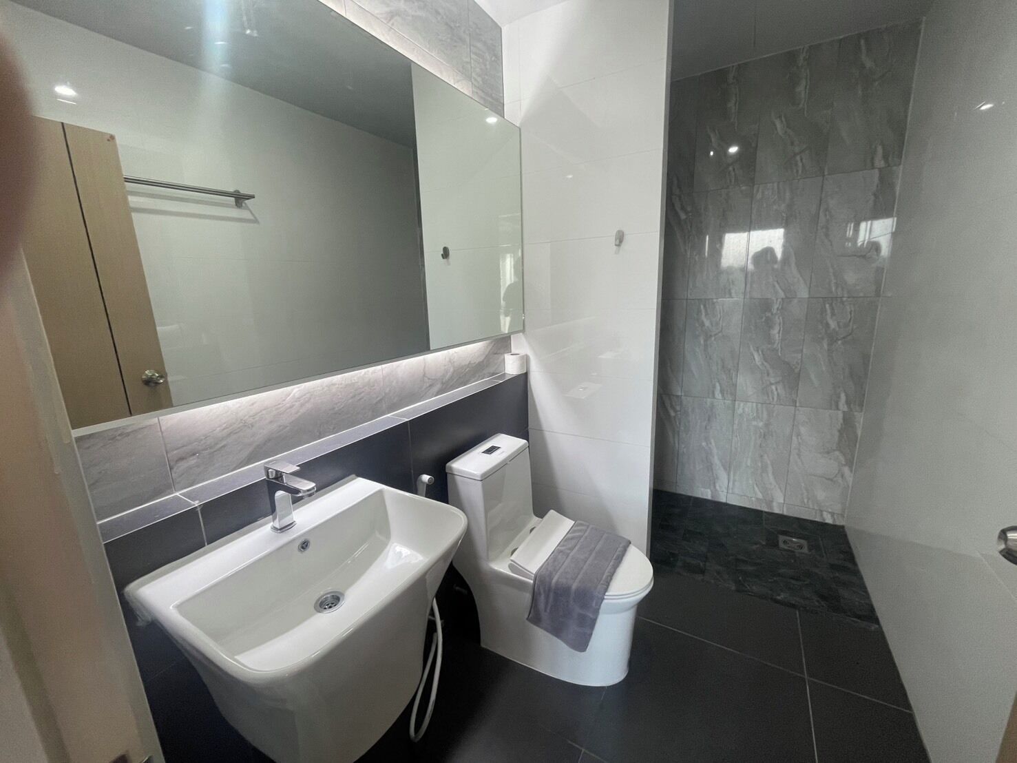 Un baño moderno con lavamanos, inodoro y zona de ducha blancos.