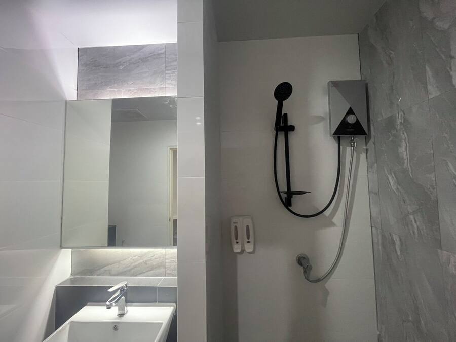 Un baño con un lavabo blanco, un espejo y una ducha empotrada con cabezal de ducha manual.