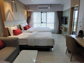 Habitación de hotel con dos camas, un escritorio, una silla, un televisor y una ventana con cortinas.