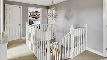 A staircase with white balusters leading to a landing with a chandelier.