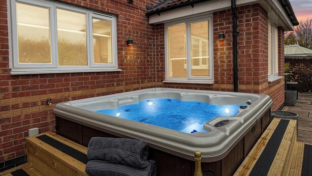 Un jacuzzi con cubierta de madera, dos toallas y dos vasos.
