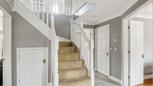 Una escalera con barandillas blancas y alfombra color beige que conduce a una plataforma.