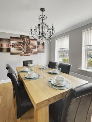 A dining area with a wooden table set for six, black leather chairs, and a chandelier.
