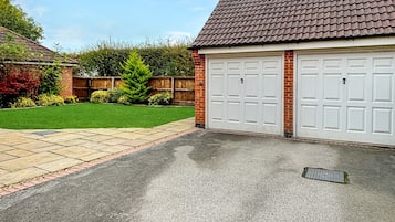 Un garage attenant à une maison, avec une allée pavée et un mur en briques.