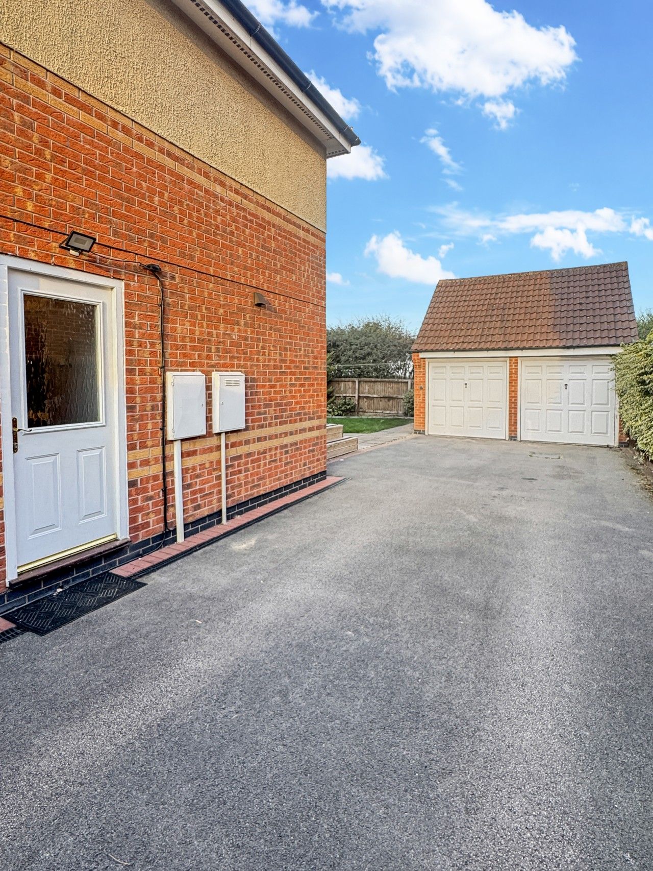 Un garage attenant à une maison, avec une façade en briques et une allée pavée.