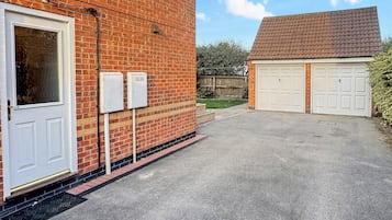 Un garage attenant à une maison, avec une façade en briques et une allée pavée.