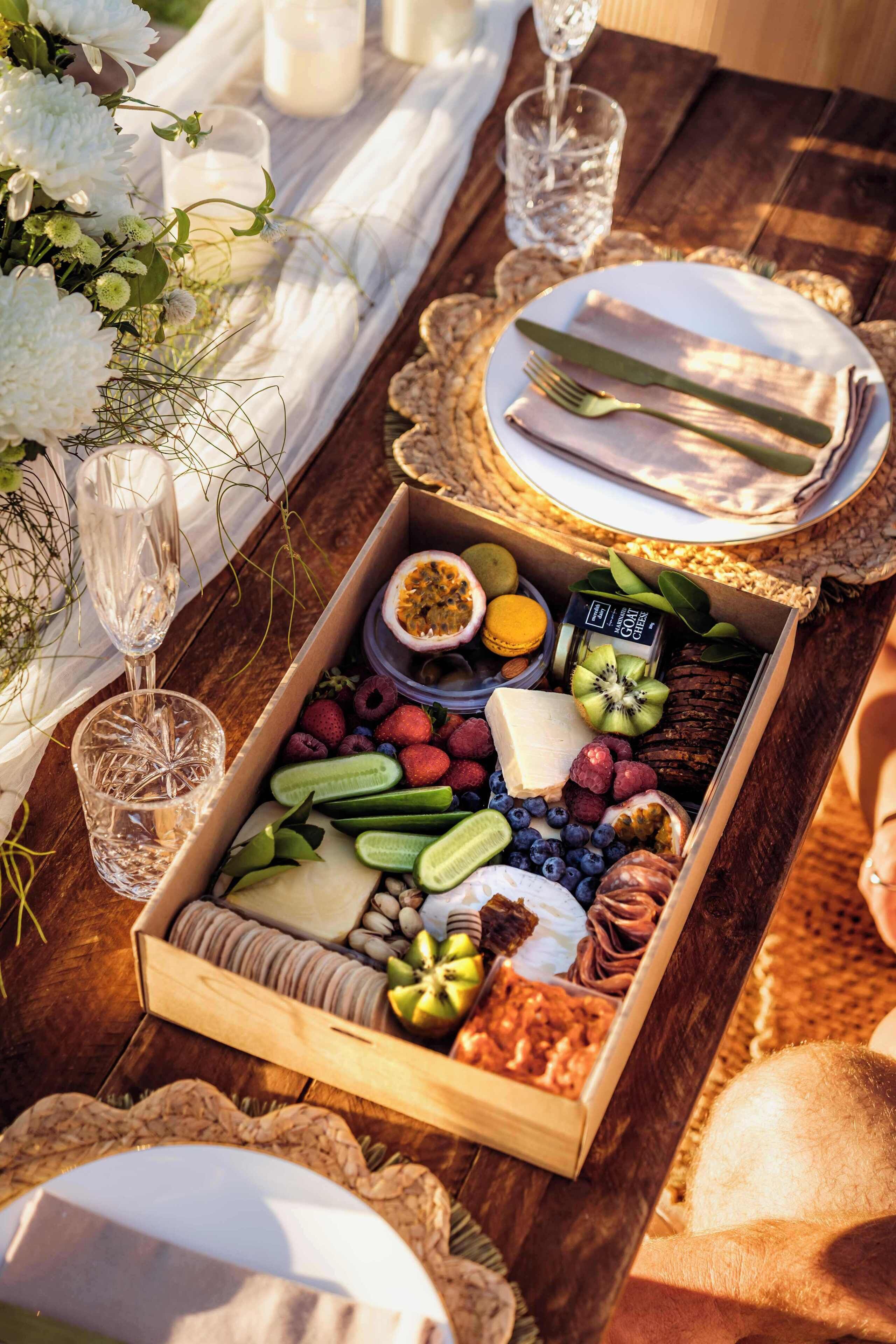 A wooden tray with a variety of snacks and a bottle of goat cheese.