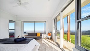 A modern bedroom with a large bed, a sofa, and a balcony with a view. - Petrichor Estate - 360 Views, Magnesium Pool & Spa (Sunshine Coast Hinterland)