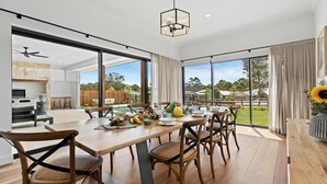 Un vaste espace dédié à la salle à manger, avec une grande table en bois, des chaises en osier et une vue sur le jardin.