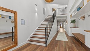 Un intérieur moderne avec un escalier en bois, des murs blancs et un couloir menant à une autre pièce.