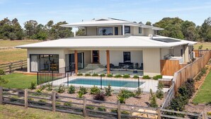 Une maison moderne à deux étages, dotée d’une grande terrasse et d’une piscine.