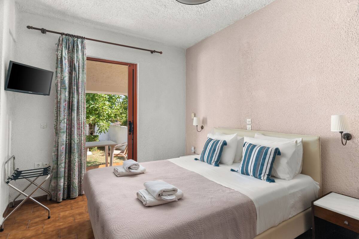 Ein Hotelzimmer mit Bett, Fernseher, Schreibtisch und einem Fenster mit Vorhängen.